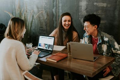 three people laughing while working on laptops