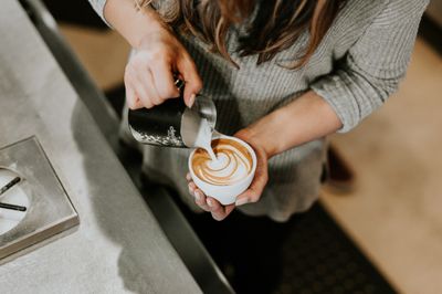 Milk being poured into a coffee in a café